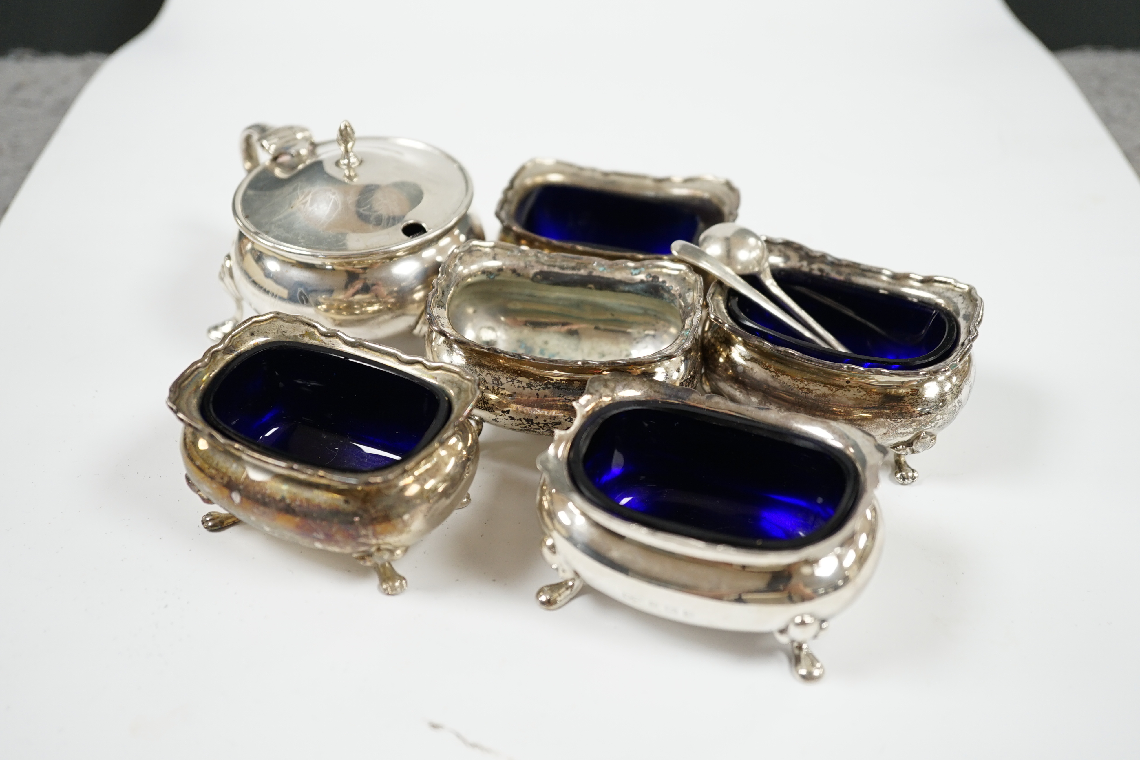 Six assorted silver condiments including a George V mustard pot, by Edward Barnard & Sons Ltd. Condition - poor to fair